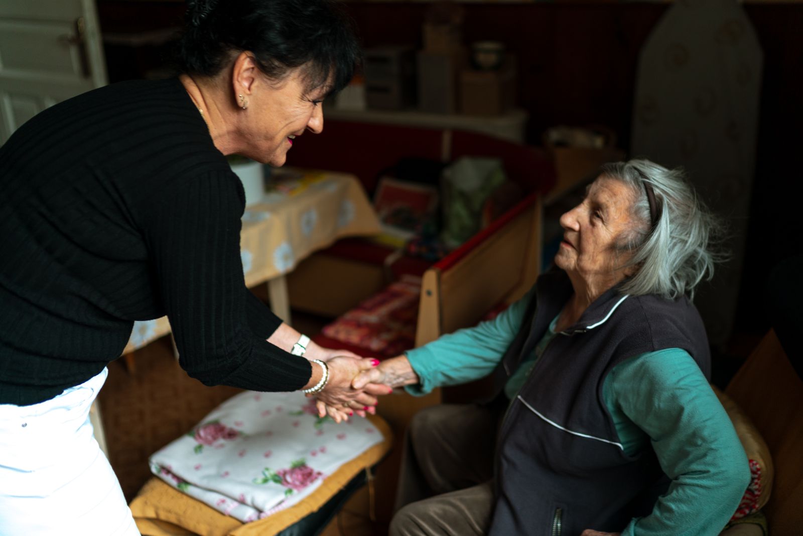 A caregiver greeting an older woman in her home