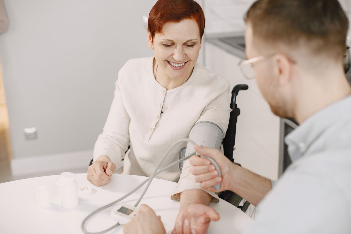 A care professional checking a woman’s blood pressure at home